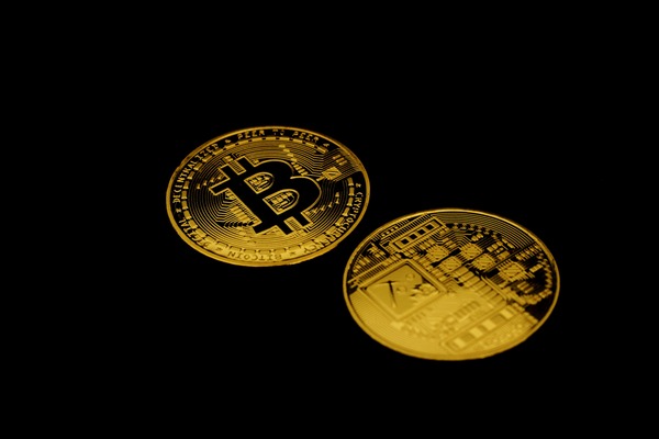 XRP coin placed next to a laptop showing market charts